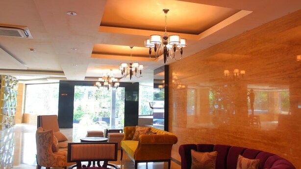 Un moderno vestíbulo de hotel con zona de estar, candelabros y grandes ventanales.