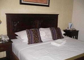 Une chambre d’hôtel avec un lit, une table de chevet avec un téléphone et un tableau encadré au mur.