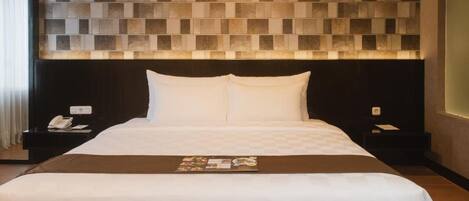 A modern hotel room with a large bed, a headboard with a geometric tile design, a bedside table with a phone, and a nightstand with a lamp.