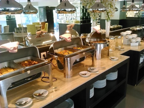 A buffet setup with multiple food stations, stainless steel serving dishes, and a variety of utensils. - Royal Regantris Cendana (Surabaya)