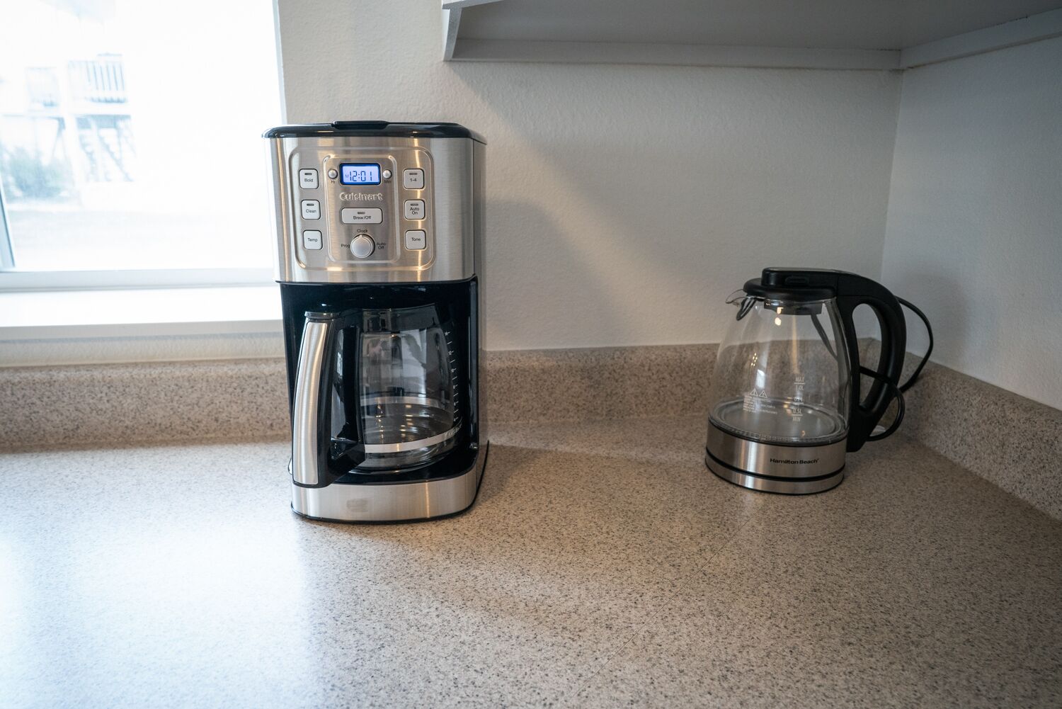 Une machine à café et une verseuse en verre sur un plan de travail de cuisine.