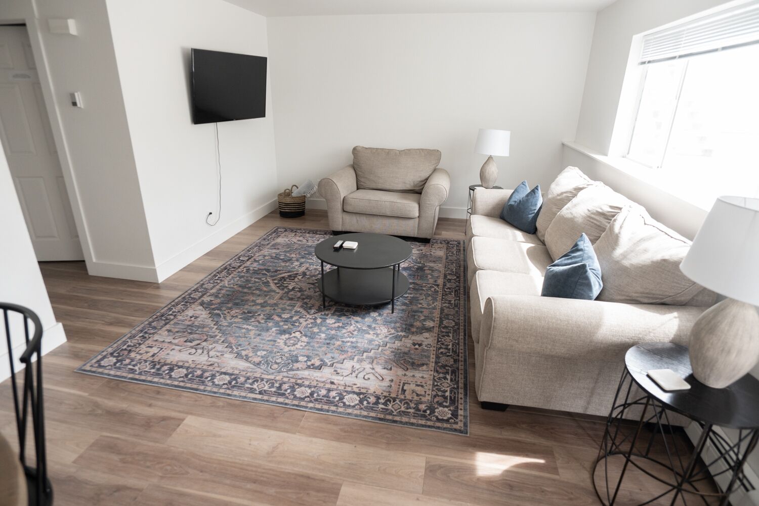A living room with a beige sofa, a black coffee table, and a patterned rug.