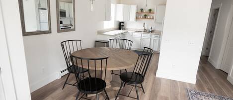 Una cocina moderna con armarios blancos, una mesa de comedor redonda de madera y sillas negras.