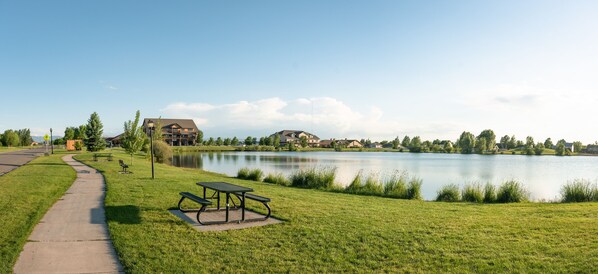 A lakeside park with picnic tables and a walking path.