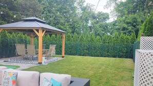 A backyard with a wooden gazebo, outdoor furniture, and a well-maintained lawn. - Cape Cod Sunscape. Orleans (Orleans)