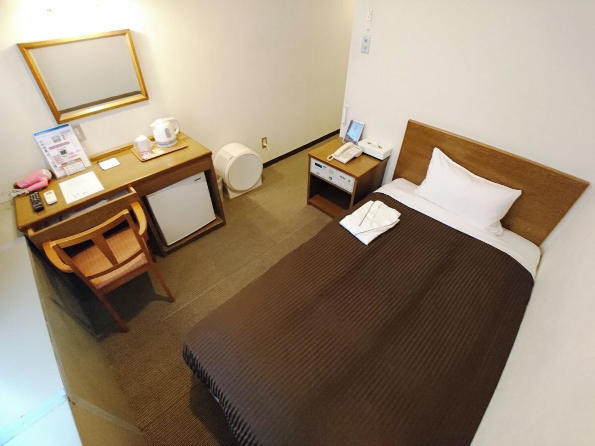 Ein Hotelzimmer mit Bett, Schreibtisch, Stuhl und kleinem Kühlschrank.