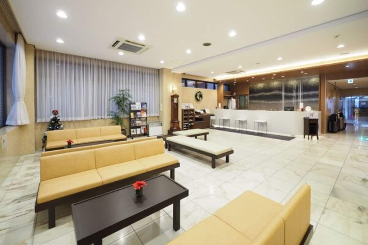 A hotel lobby with seating areas, a reception desk, and a large window.