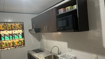 Een keuken met donkere houten kastjes, een ingebouwde magnetron, een roestvrijstalen spoelbak en een decoratief wandobject.