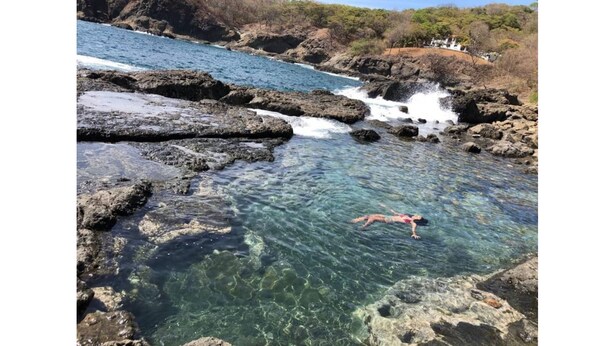 Un plan d’eau aux eaux claires, parsemé de formations rocheuses, où une personne est en train de nager.