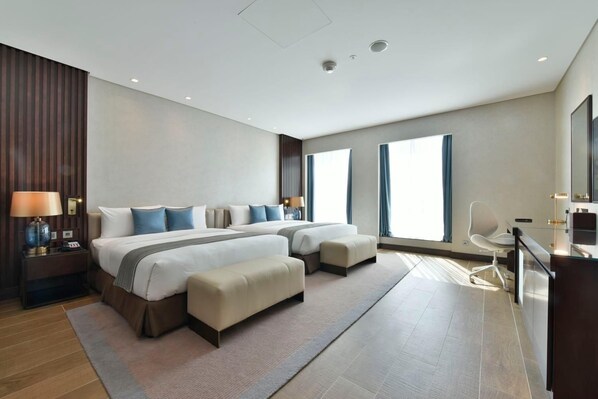Una habitación de hotel moderna con una cama grande, dos mesitas de noche, un escritorio y una silla.