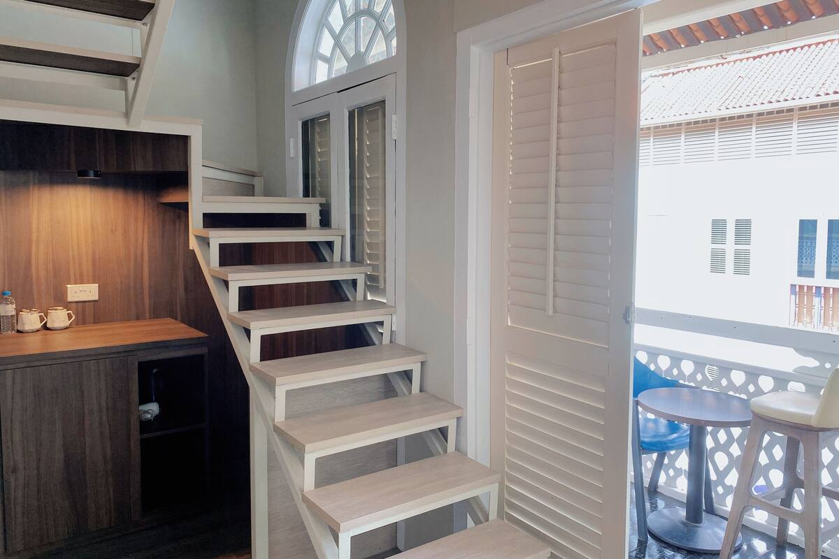 A staircase with white steps leading to a room with a wooden wall and a window.