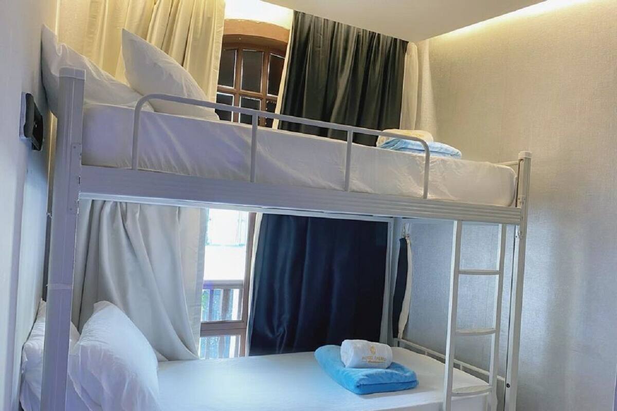 A bunk bed with white bedding and a blue towel.