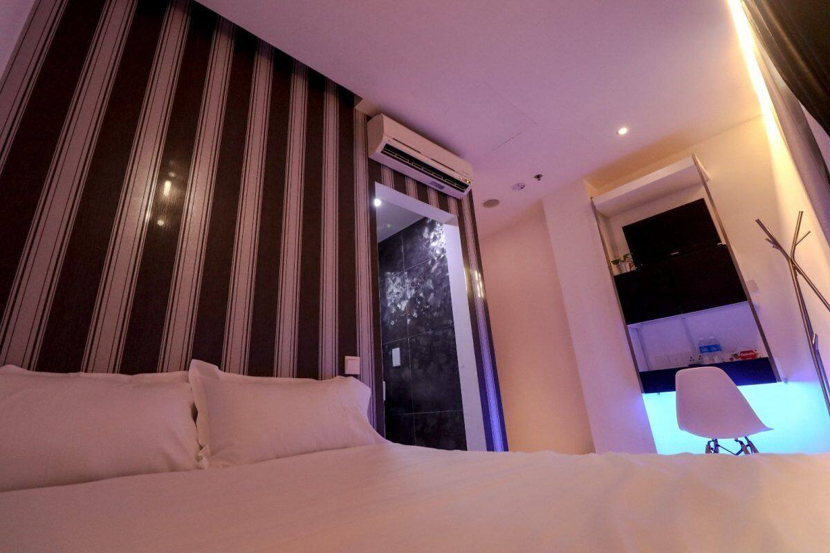A hotel room with a bed, a mirror, a wardrobe, and a desk with a chair.