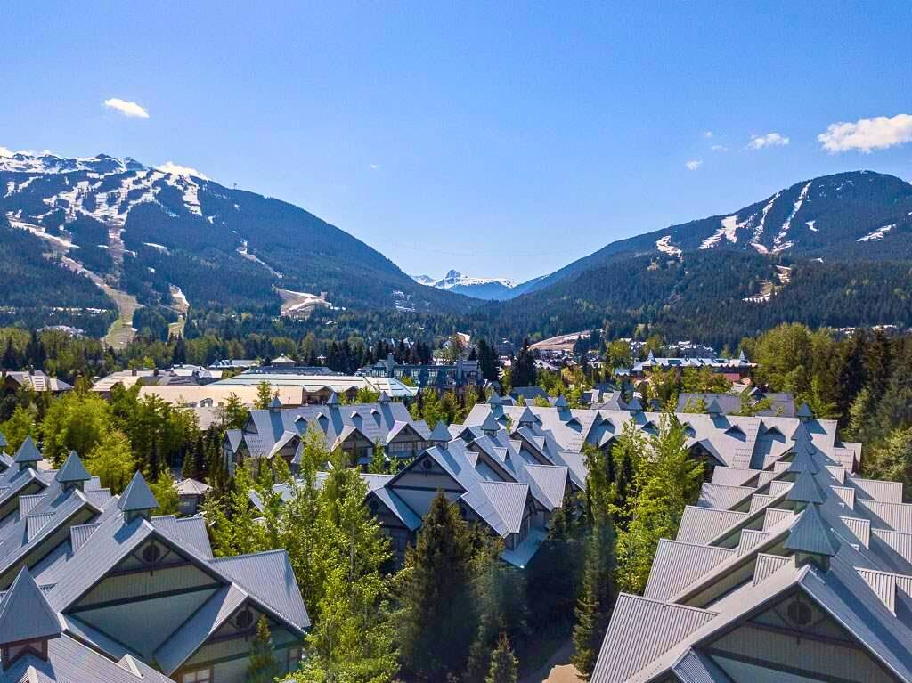 Een resort met meerdere gebouwen in chaletstijl, een skipiste op de achtergrond en een bergachtig landschap.