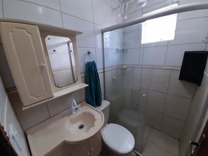 A bathroom with a toilet, sink, mirror, and shower area. - Exclusive Pool (Planaltina)
