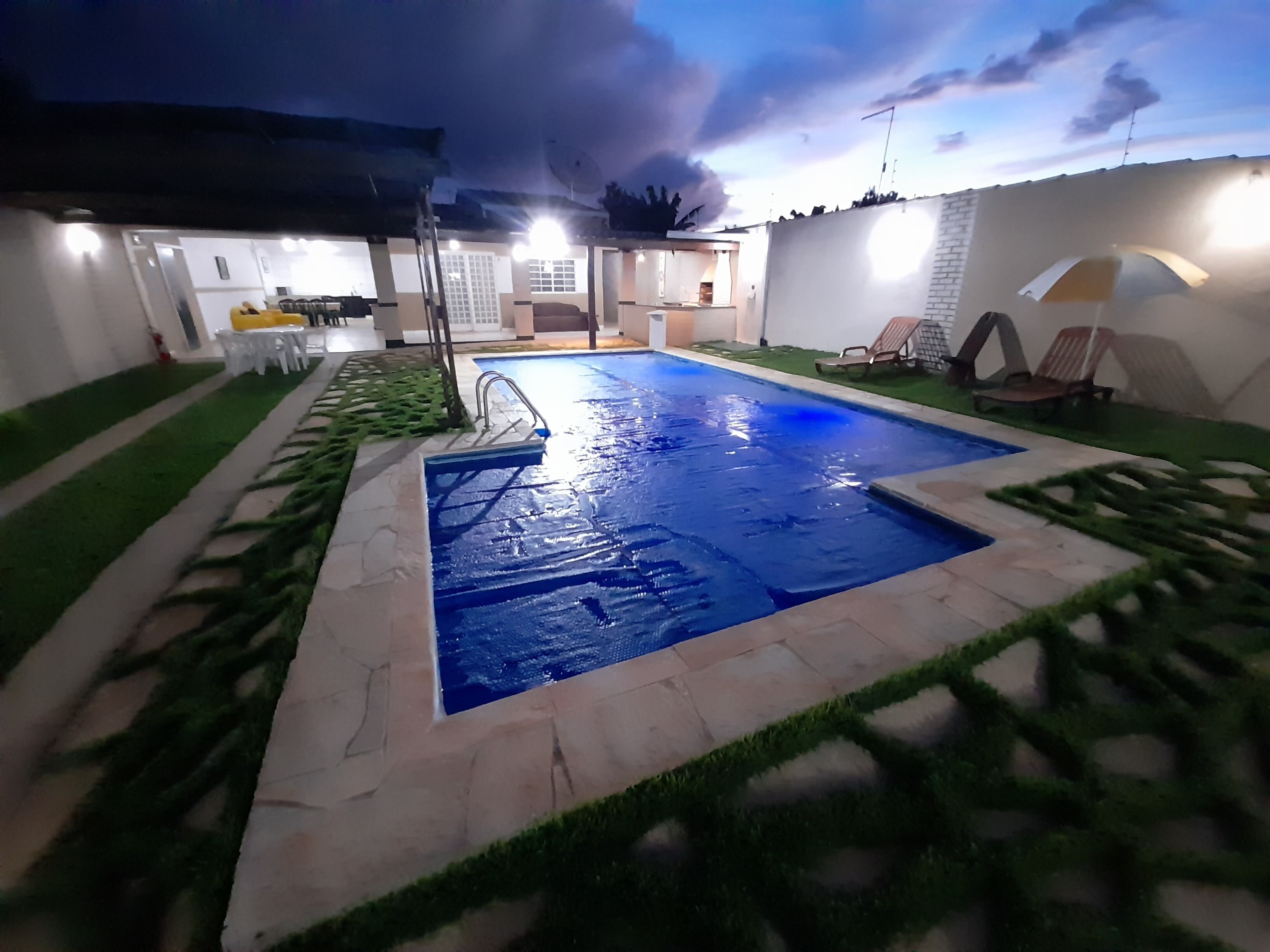 Una piscina con una solana empaveda y un tobogán pequeño.
