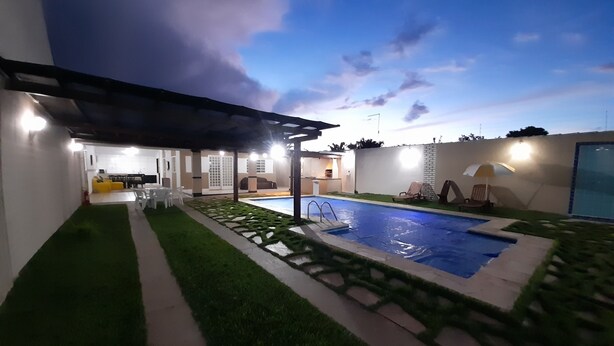 A modern outdoor pool area with a pergola, artificial grass, and a patio with seating. - Exclusive Pool  (Planaltina)