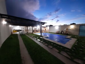 A modern outdoor pool area with a pergola, artificial grass, and a patio with seating. - Exclusive Pool (Planaltina)