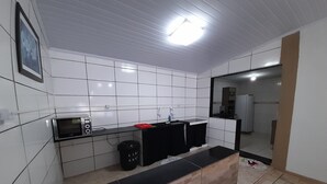 A modern kitchen with white tiles, a black countertop, and a built-in oven. - Exclusive Pool  (Planaltina)