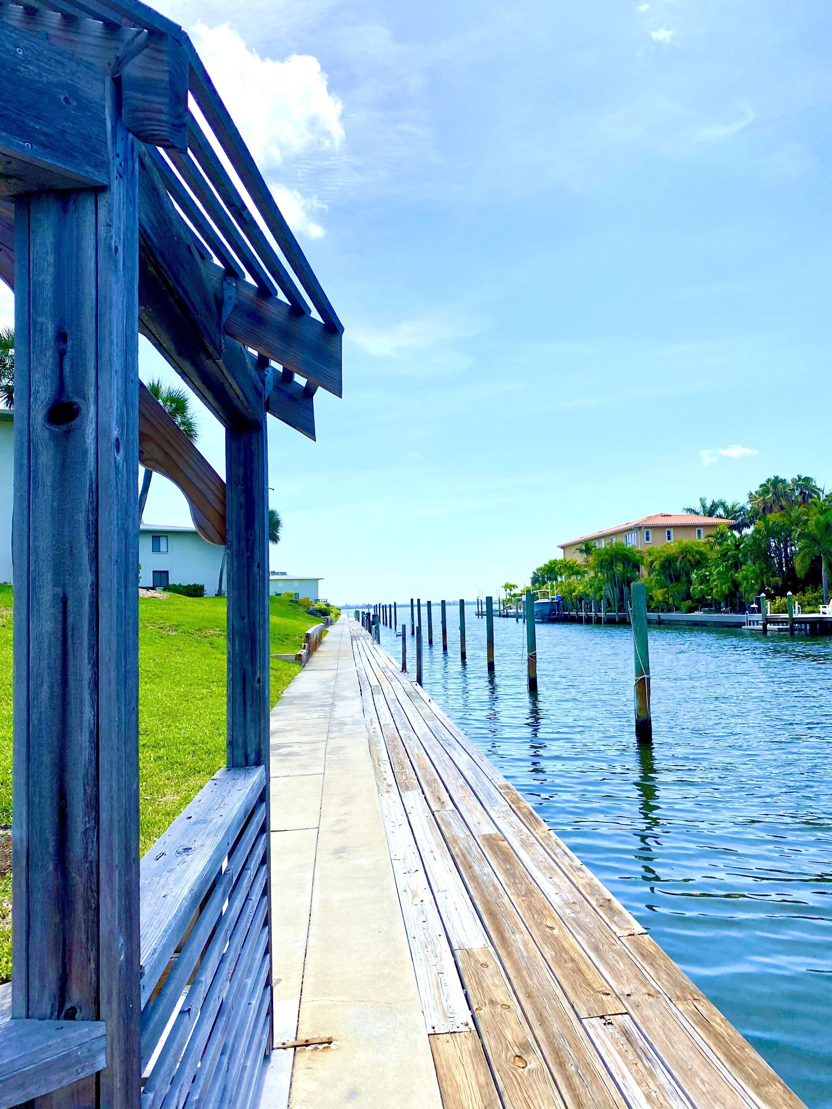 A wooden boardwalk extending over water, with a building in the background.