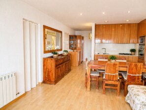 Una cucina con mobili in legno, un tavolo da pranzo con sedie, uno specchio e un termosifone.