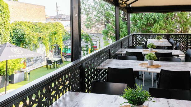 An outdoor patio with tables and chairs, a covered area, and a view of the surrounding greenery. - Palace Hotel Mortlake (Mortlake)