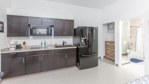 A modern kitchen with dark cabinets, a microwave, a refrigerator, and a sink. - Chugach Mountains View South Anch Premium Suite (Anchorage)