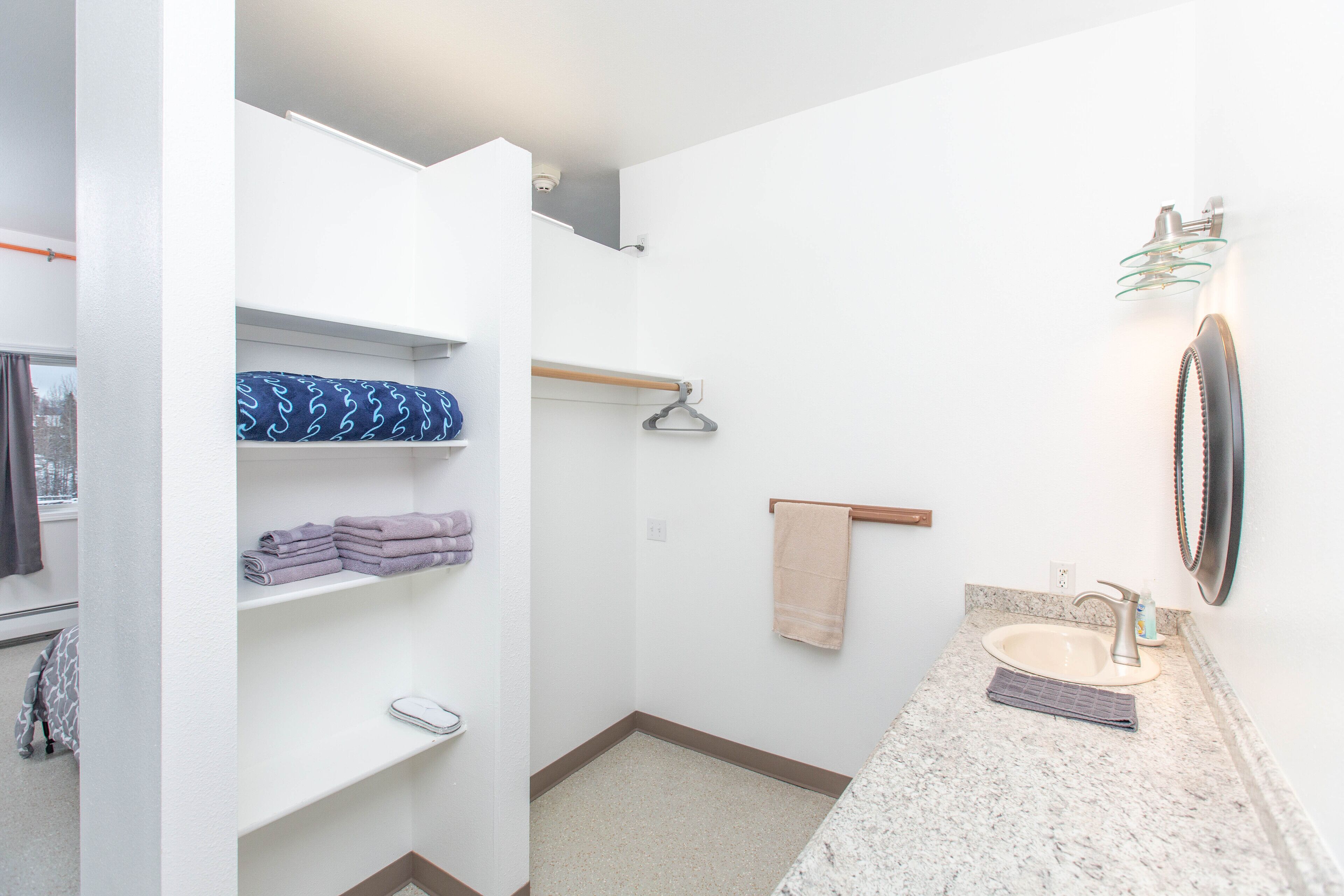 Une salle de bain équipée d’un lavabo, d’un miroir, d’un porte-serviettes et d’étagères où sont rangées les serviettes.