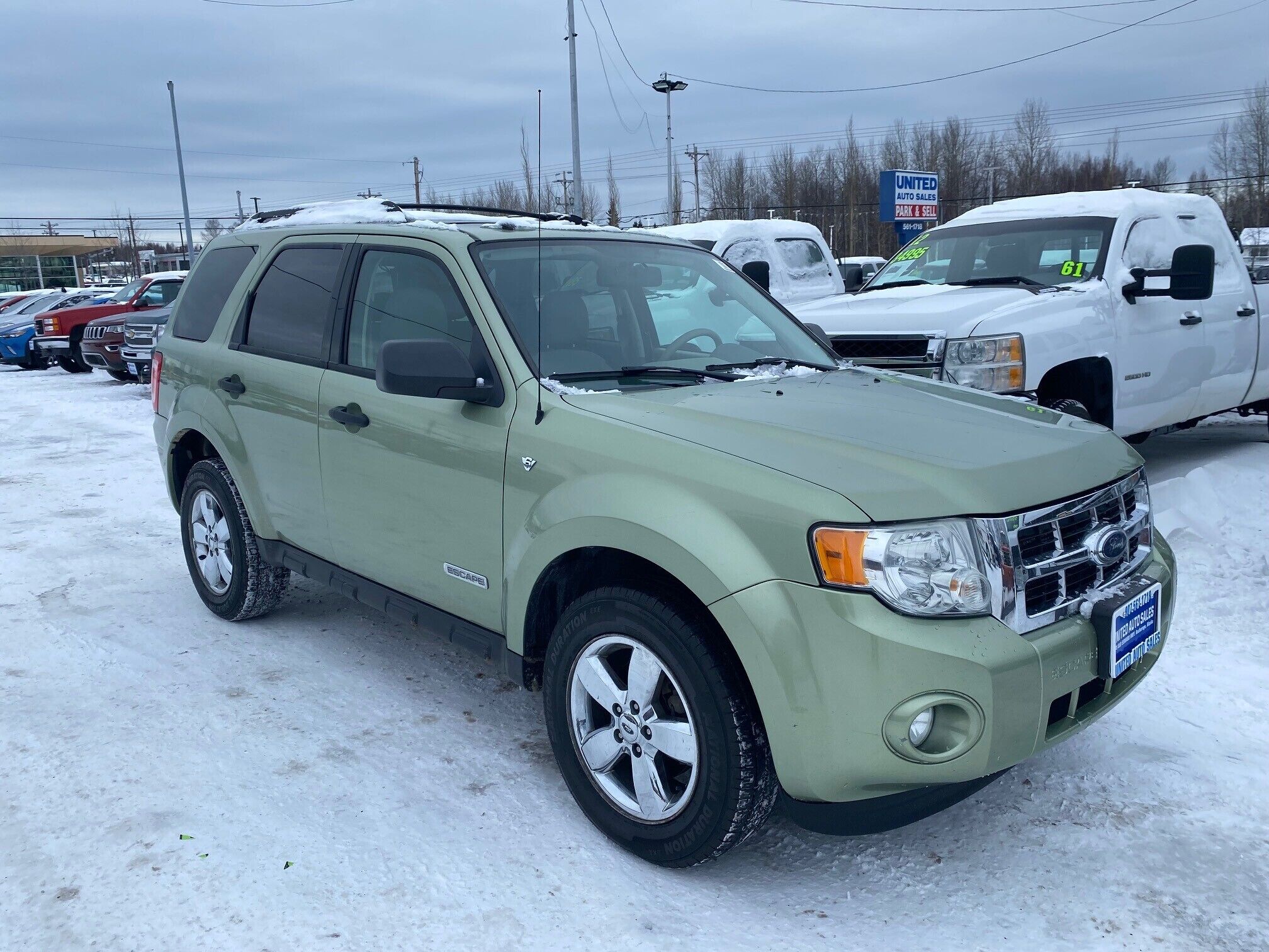 A light green SUV parked in a snowy lot with other vehicles.