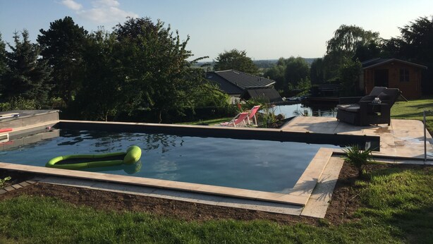 A swimming pool with a view of a house and trees in the background. - Moni's chicken farm Pure nature Outdoor pool for shared use (Nettetal)