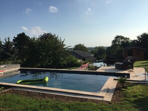 A swimming pool with a view of a house and trees in the background.