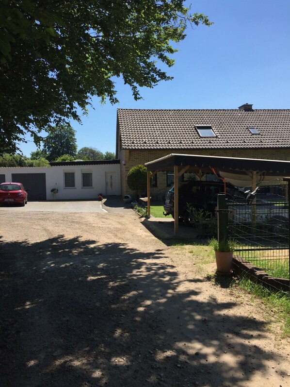 A building with a tiled roof, a covered porch, and a fenced area with a potted plant.