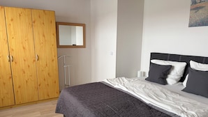 A bedroom with a bed, a wooden wardrobe, a mirror, and a painting on the wall. - Moni's chicken farm Pure nature Outdoor pool for shared use (Nettetal)