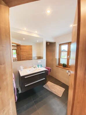 Une salle de bain moderne avec un grand miroir, un meuble-lavabo et une fenêtre donnant sur un beau paysage.
