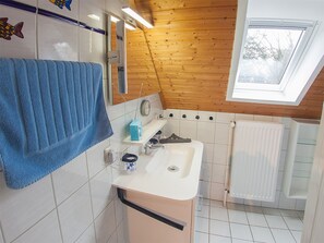 A bathroom with a wooden ceiling, a skylight, a sink, a mirror, and a towel rack. - Ferienhaus Kickler, Vermietungsservice Dangast - Ferienhaus Kickler (Varel)