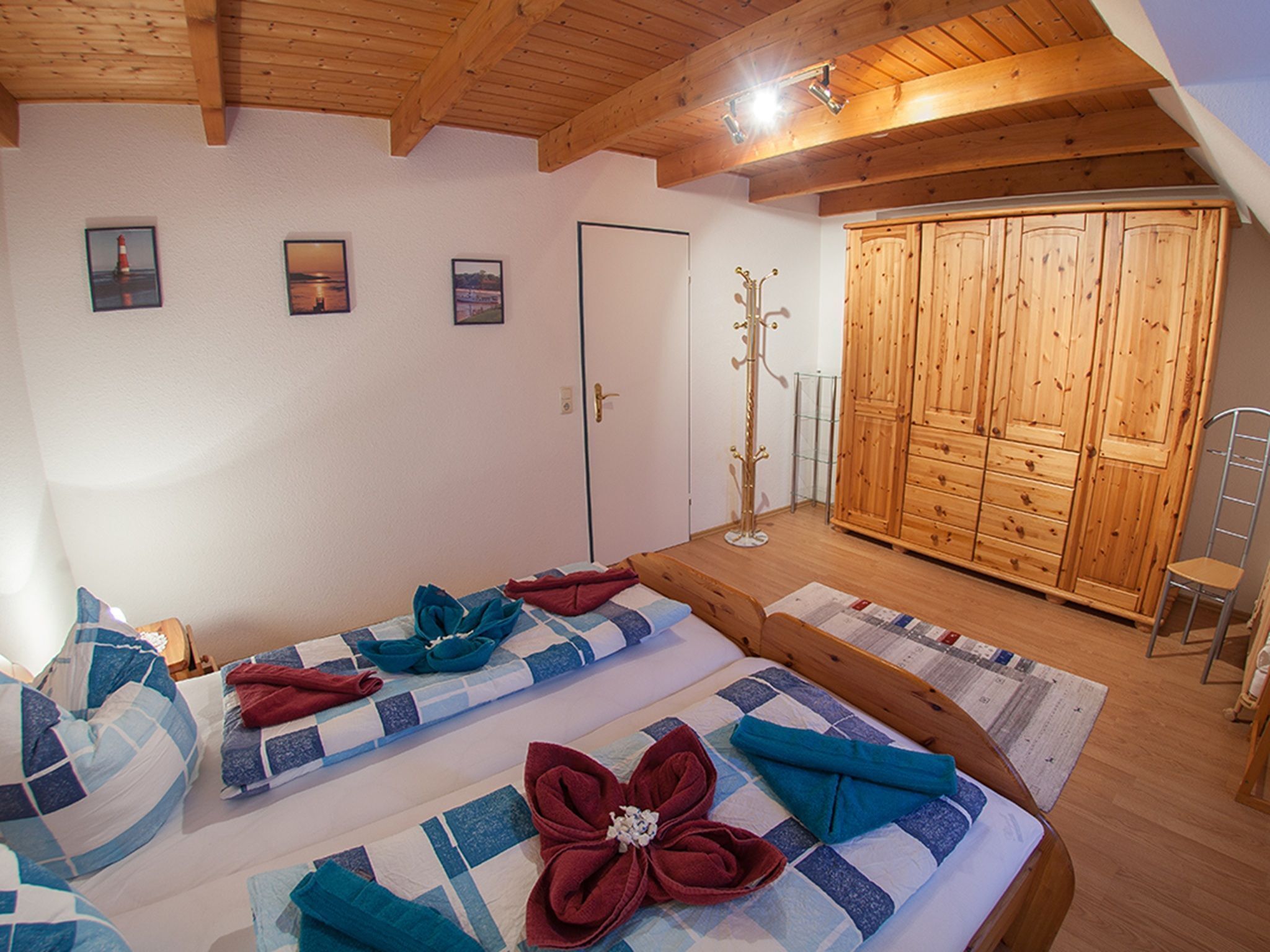 Une chambre avec deux lits, une armoire et un porte-manteau.