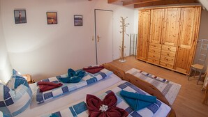 Een kamer met twee bedden, een kledingkast en een kapstok.