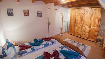 Une chambre avec deux lits, une armoire et un porte-manteau.
