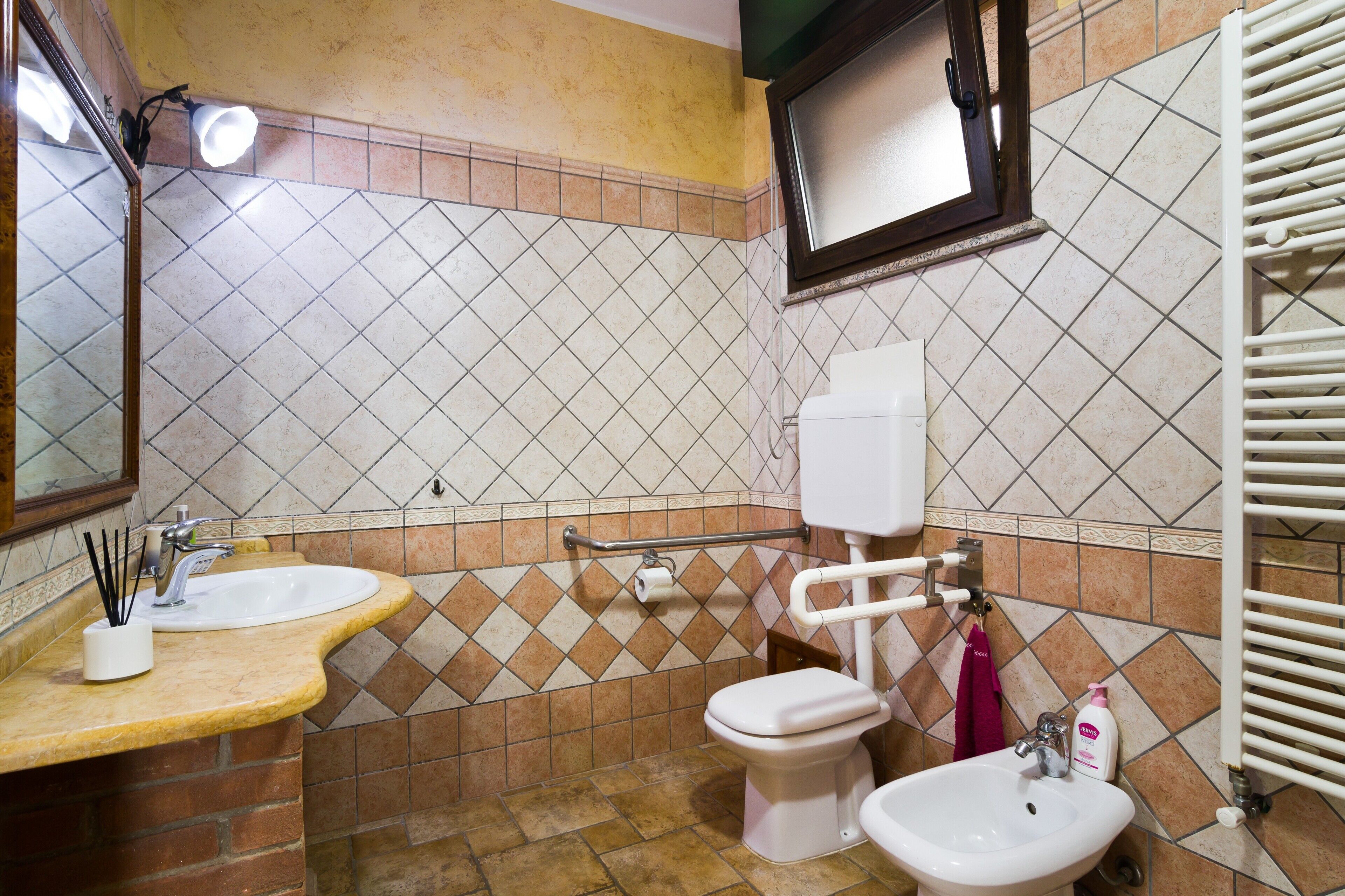 Ein Badezimmer mit Waschbecken, Toilette und Bidet, mit gefliestem Rücksprühefeld und Spiegel.