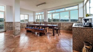 A spacious kitchen with a large dining table, ample natural light, and a view of the landscape.