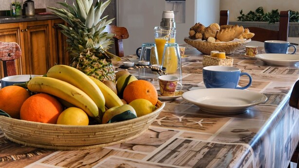 A breakfast table with fruits, a blender, and a coffee maker.