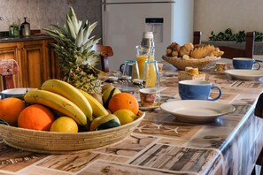 A breakfast table with fruits, a blender, and a coffee maker.