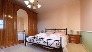 A bedroom with a bed, wooden wardrobe, and a nightstand.