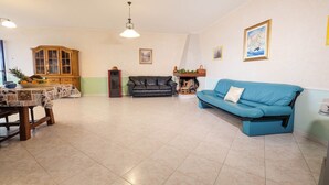 A spacious living room with a dining area, a fireplace, and a blue sofa.