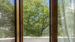 A balcony with a view of trees and a metal railing.