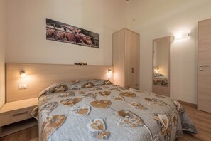 A bedroom with a bed, a wardrobe, a mirror, and a wall-mounted picture. - Apartment "Nonno Bigi Tulipano" with Mountain View, Wi-Fi, Balcony & Garden (Tremosine sul Garda)