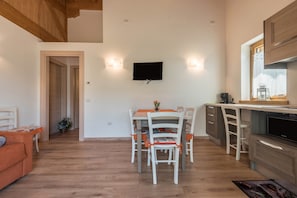 Eine moderne Küche mit Essbereich, Holzboden und einem an der Wand befestigten Flachbildfernseher.