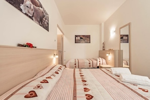 Une chambre d’hôtel avec deux lits, un grand miroir et un tableau au mur.