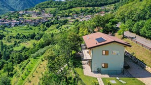 Un village rural avec des maisons construites sur une colline, un petit bâtiment équipé d’un panneau solaire et une route asphaltée.