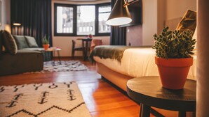 Une pièce confortable avec un lit, une petite table, une plante en pot et une lampe.